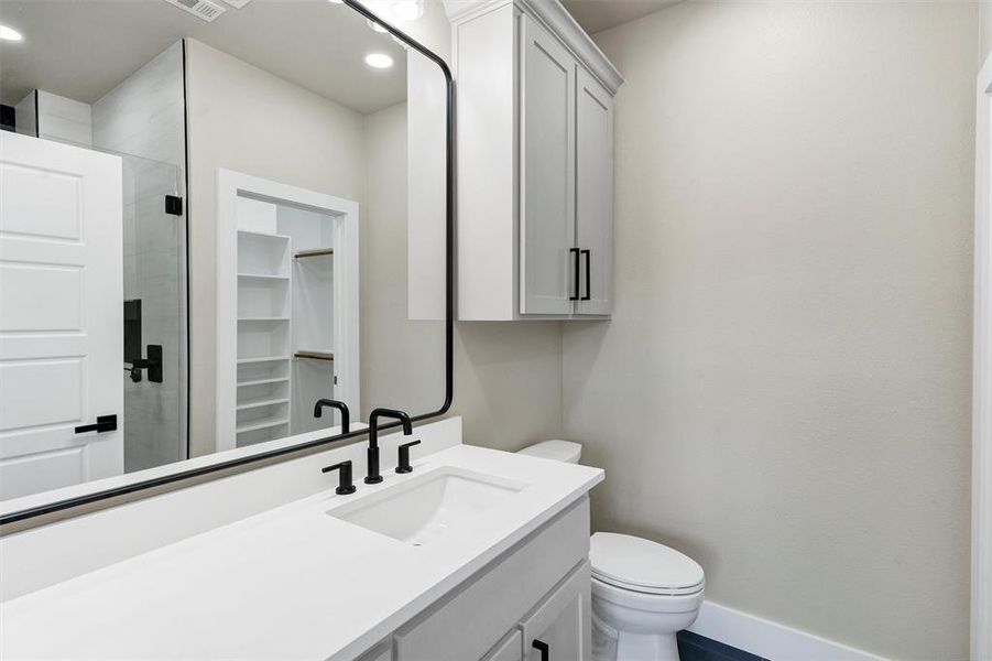 Bathroom featuring vanity, a shower with shower door, and toilet