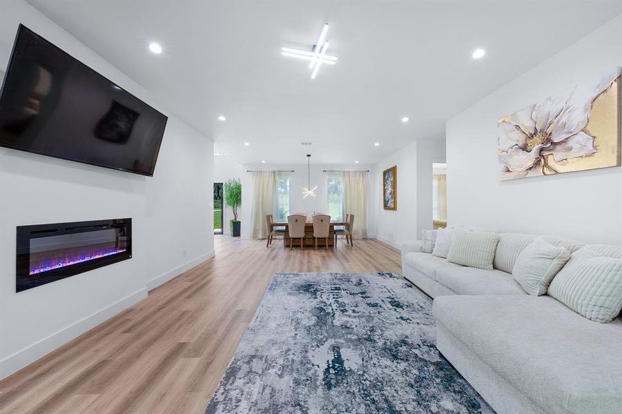 Living room with a glass covered fireplace, recessed lighting, and light wood-style flooring Living room with a glass covered fireplace, recessed lighting, and light wood-style flooring