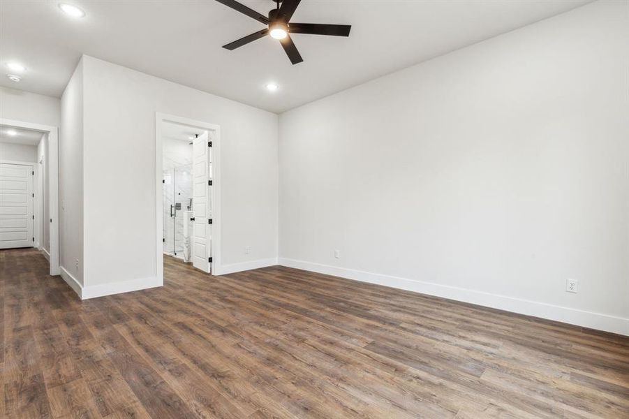 Empty room featuring ceiling fan and dark hardwood / wood-style flooring