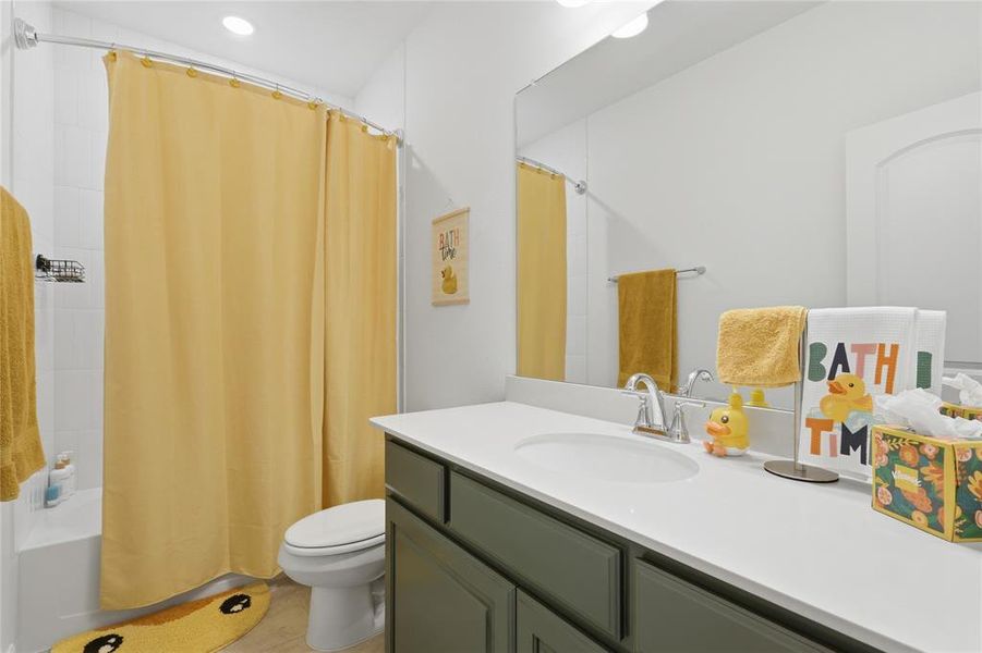 Full bathroom featuring a single vanity with a white countertop, undermount sink, and dark green cabinetry Full bathroom featuring a single vanity with a white countertop, undermount sink, and dark green cabinetry