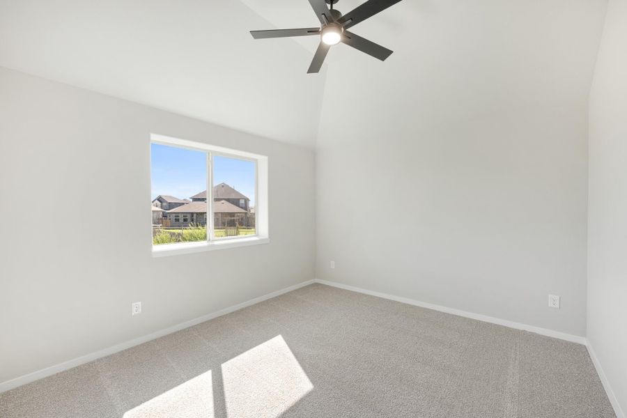 Empty bedroom with vaulted ceiling, ceiling fan, carpet flooring, and a single window