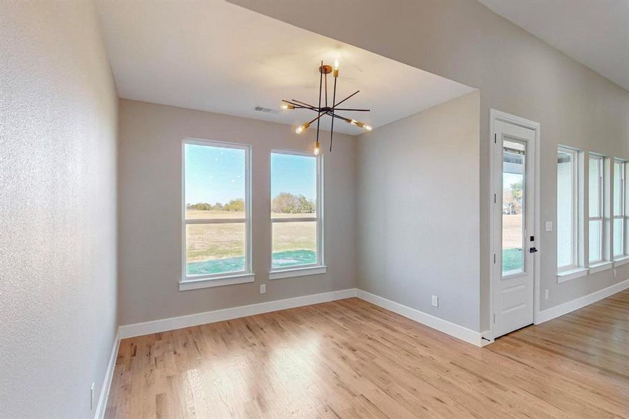 Spare room with a chandelier and light hardwood / wood-style flooring