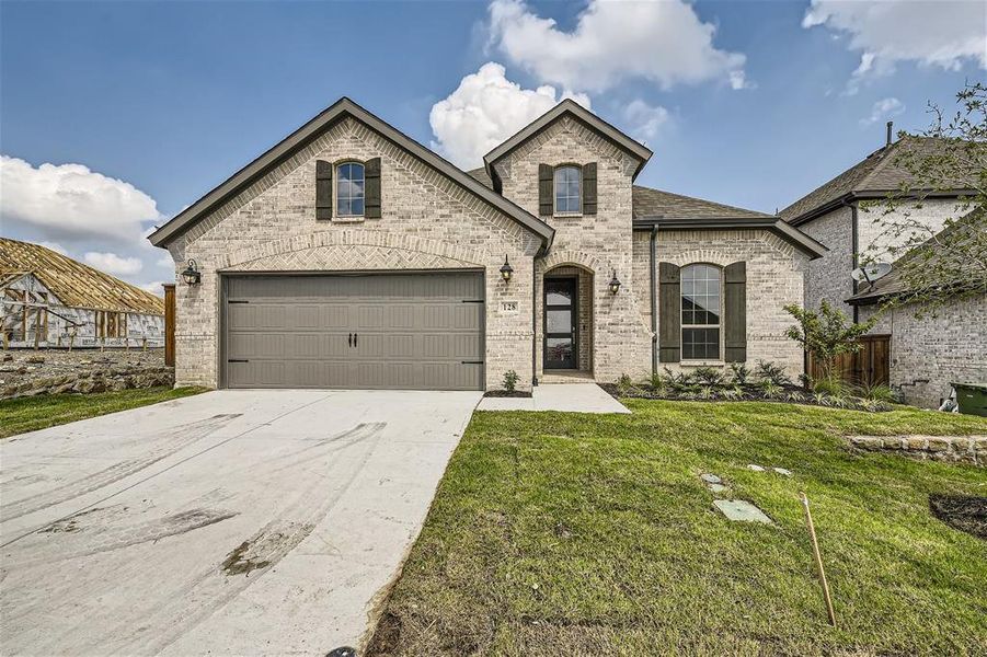 French country style house featuring a garage and a front lawn