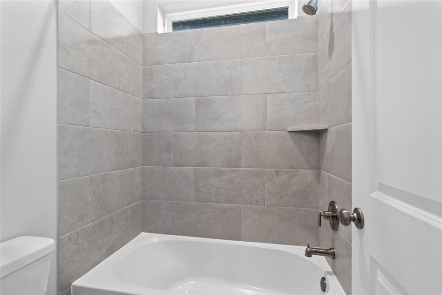 This modern bathroom features a tub/shower combination with tile surround.