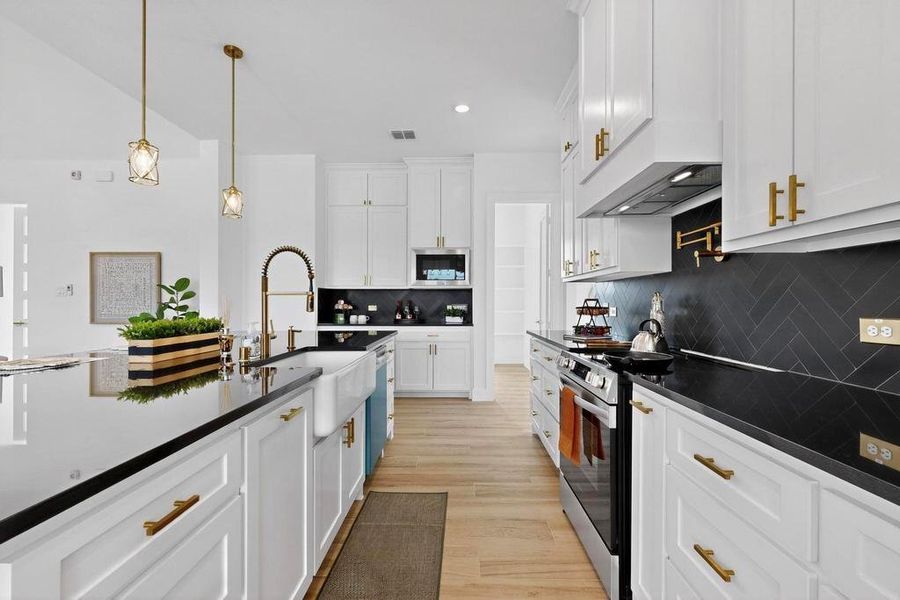 Kitchen with white cabinetry, decorative light fixtures, stainless steel appliances, light wood-type flooring, and recessed lighting
