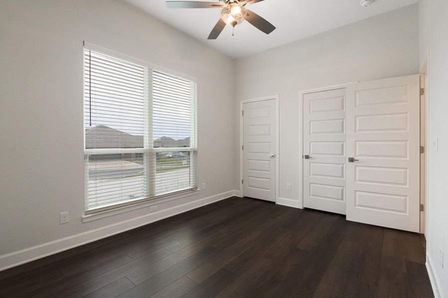 Unfurnished bedroom featuring two closets, dark wood-style flooring, and a ceiling fan