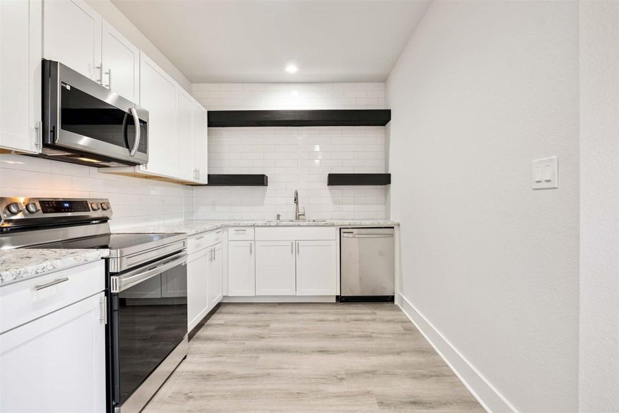 Open shelving, Shaker-style cabinets and Samsung appliances plus ceramic tile counter-to-ceiling backsplash and granite countertops