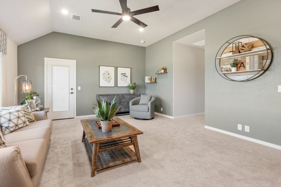 Living room with vaulted ceiling, ceiling fan, carpet flooring, and gray walls with decorative shelving