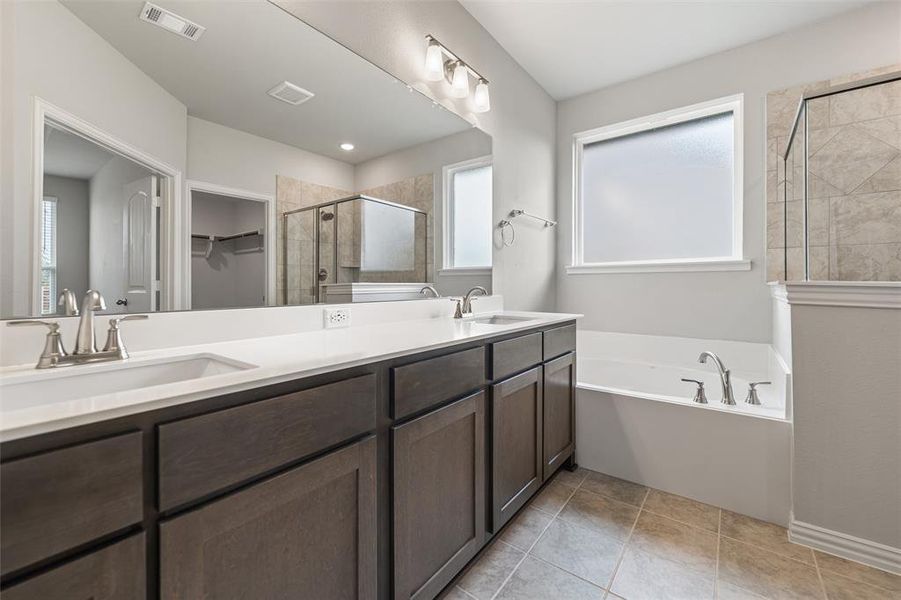 Bathroom featuring a shower stall, double vanity, a bath, and plenty of natural light Bathroom featuring a shower stall, double vanity, a bath, and plenty of natural light