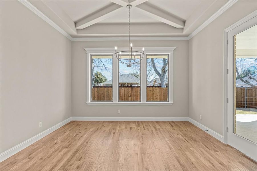 Unfurnished dining area with coffered ceiling, crown molding, a chandelier, beam ceiling, and light hardwood / wood-style floors