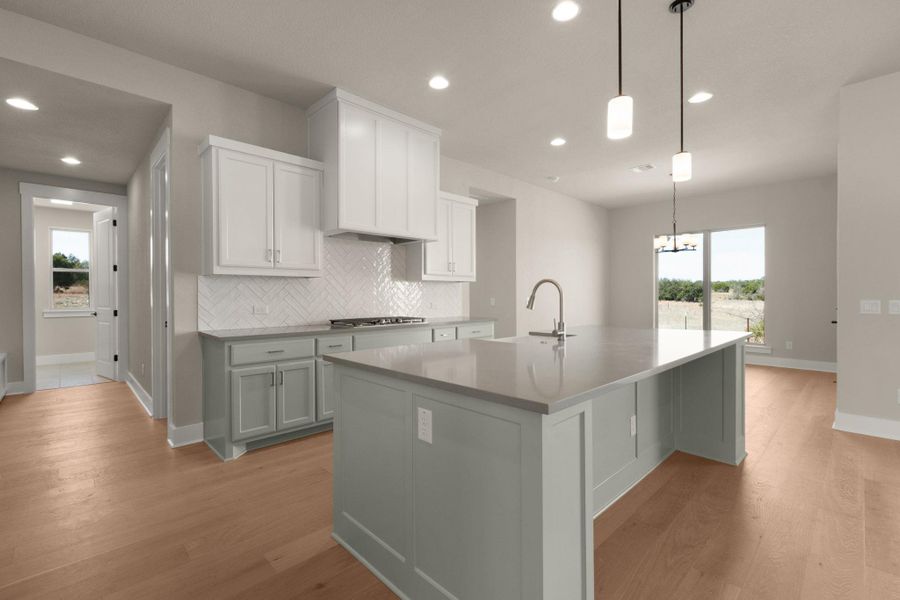 Kitchen with white cabinetry, pendant lighting, a kitchen island with sink, tasteful backsplash, and healthy amount of natural light