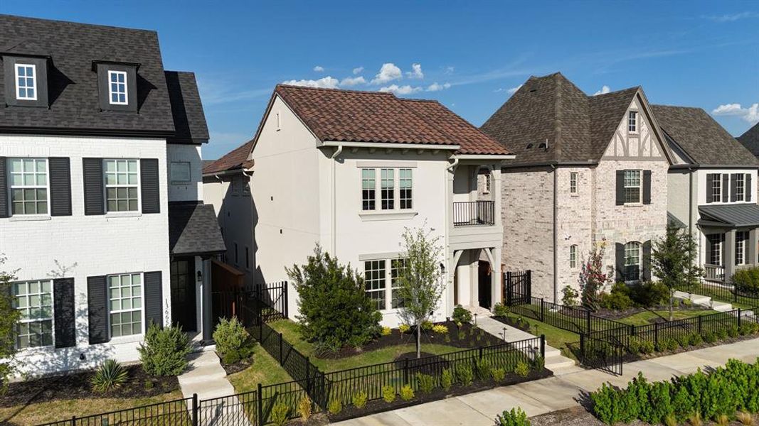 Contemporary stucco exterior featuring a red tile roof, wrought iron balcony, and front entry porch with an arched opening