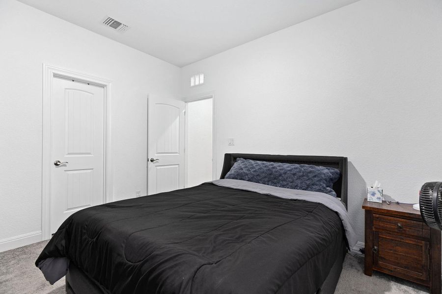 A well-lit bedroom with fresh white walls and soft carpeting provides a peaceful retreat.