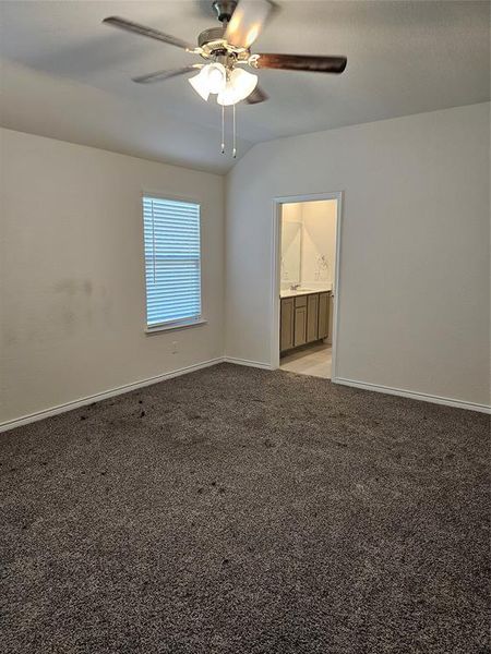 Carpeted empty room with vaulted ceiling and ceiling fan