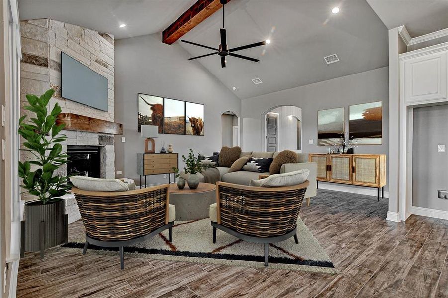 Living room featuring high vaulted ceiling, ceiling fan, beamed ceiling, and a stone fireplace