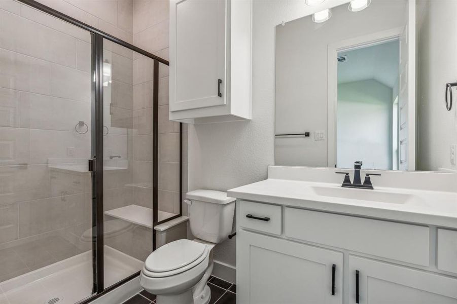 Bathroom featuring lofted ceiling, vanity, toilet, and a shower with shower door