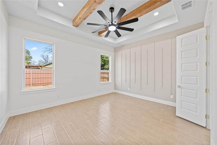 Empty room featuring a tray ceiling, wood tiled floors, ceiling fan, recessed lighting, and beamed ceiling Empty room featuring a tray ceiling, wood tiled floors, ceiling fan, recessed lighting, and beamed ceiling