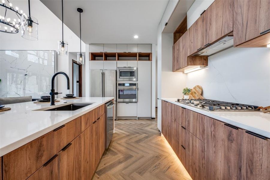 Kitchen with appliances with stainless steel finishes, modern cabinets, recessed lighting, brown cabinets, and decorative light fixtures Kitchen with appliances with stainless steel finishes, modern cabinets, recessed lighting, brown cabinets, and decorative light fixtures