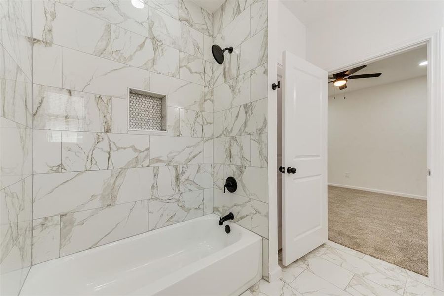 Bathroom with ceiling fan and tiled shower / bath combo