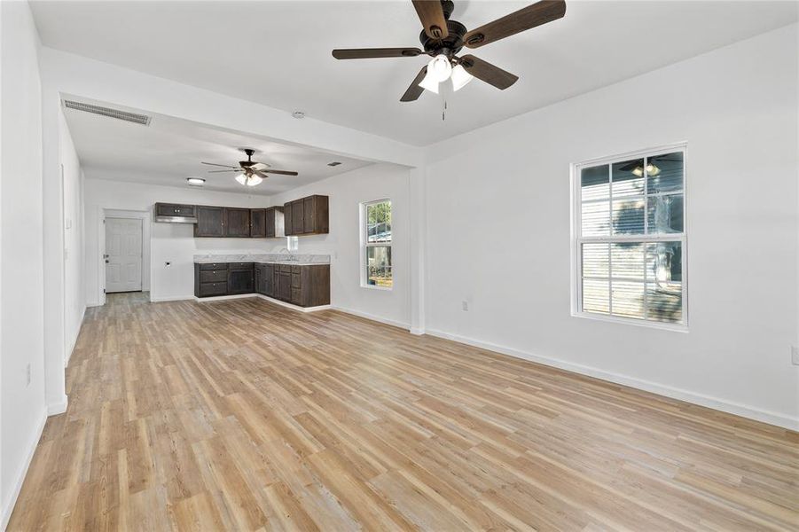 Unfurnished living room featuring light wood-type flooring and a ceiling fan Unfurnished living room featuring light wood-type flooring and a ceiling fan
