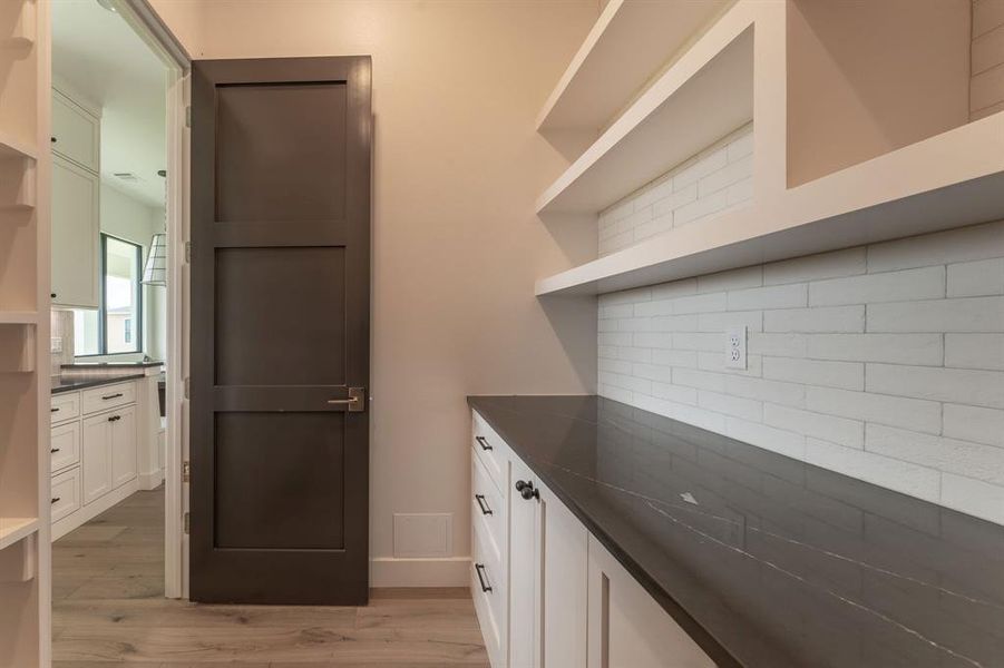 Kitchen with open shelves, white cabinets, light wood-type flooring, and backsplash Kitchen with open shelves, white cabinets, light wood-type flooring, and backsplash