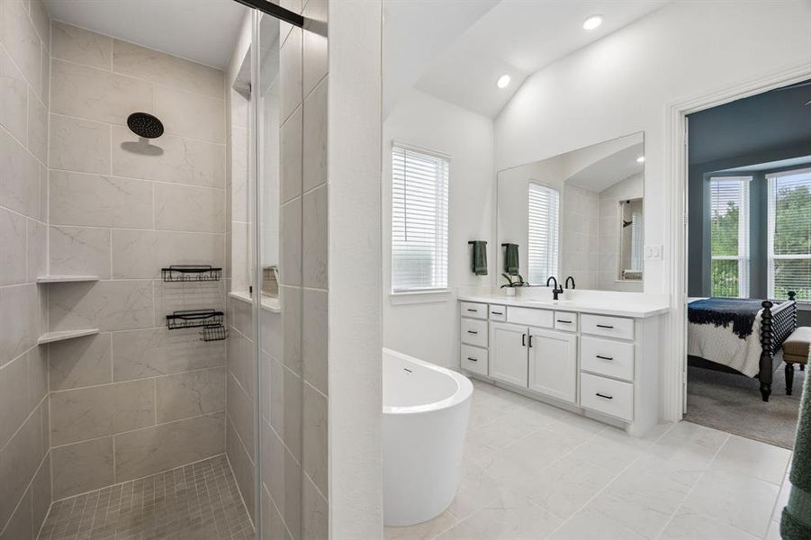 Modern bathroom featuring a freestanding tub, a dual vanity with white cabinetry and dark hardware, and a spacious walk-in shower with tile surround and dark fixtures Modern bathroom featuring a freestanding tub, a dual vanity with white cabinetry and dark hardware, and a spacious walk-in shower with tile surround and dark fixtures