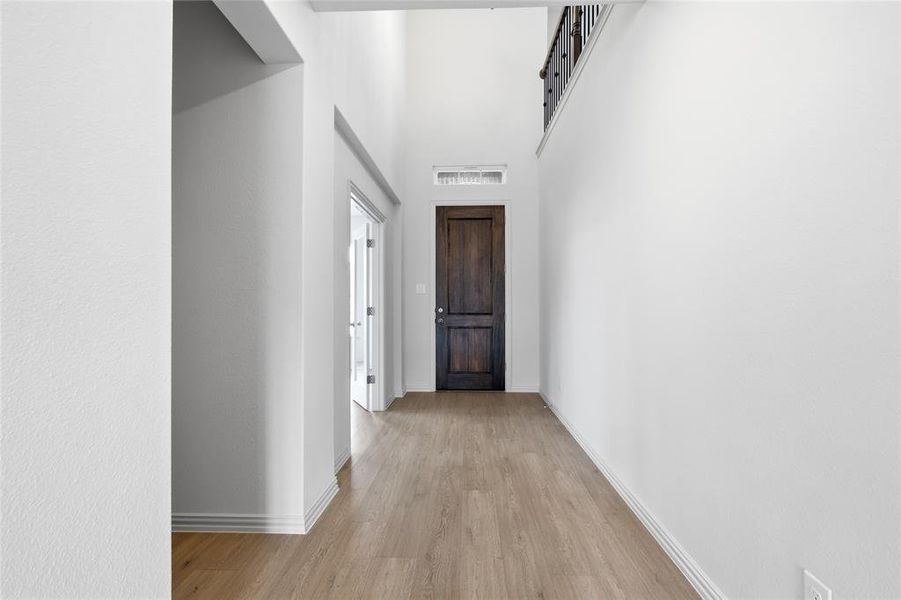 Hallway with a high ceiling and light wood-style flooring