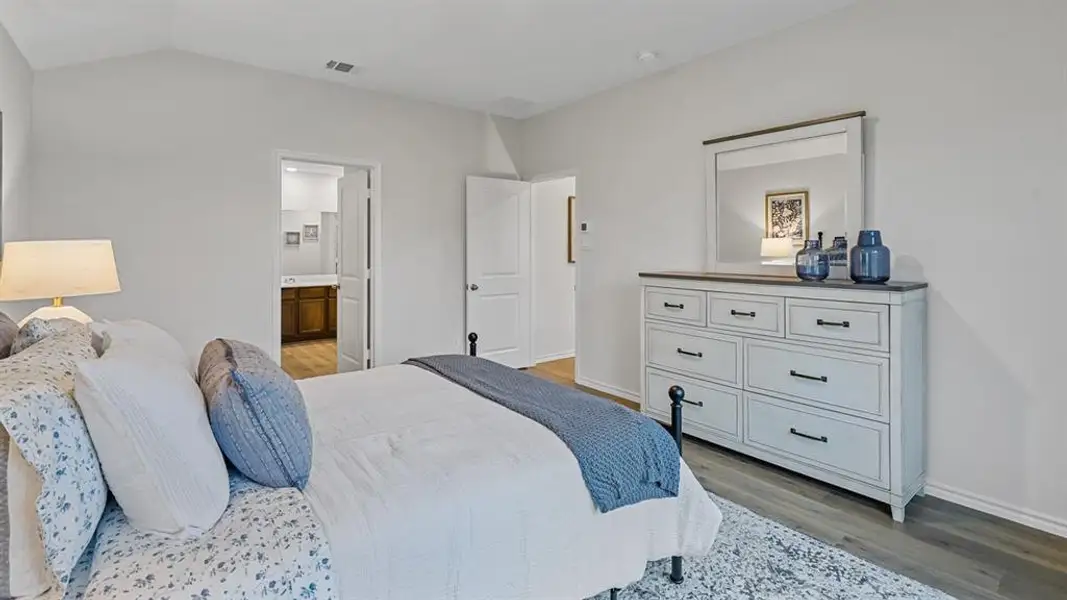 Bedroom with light wood finished floors, vaulted ceiling, and connected bathroom Bedroom with light wood finished floors, vaulted ceiling, and connected bathroom