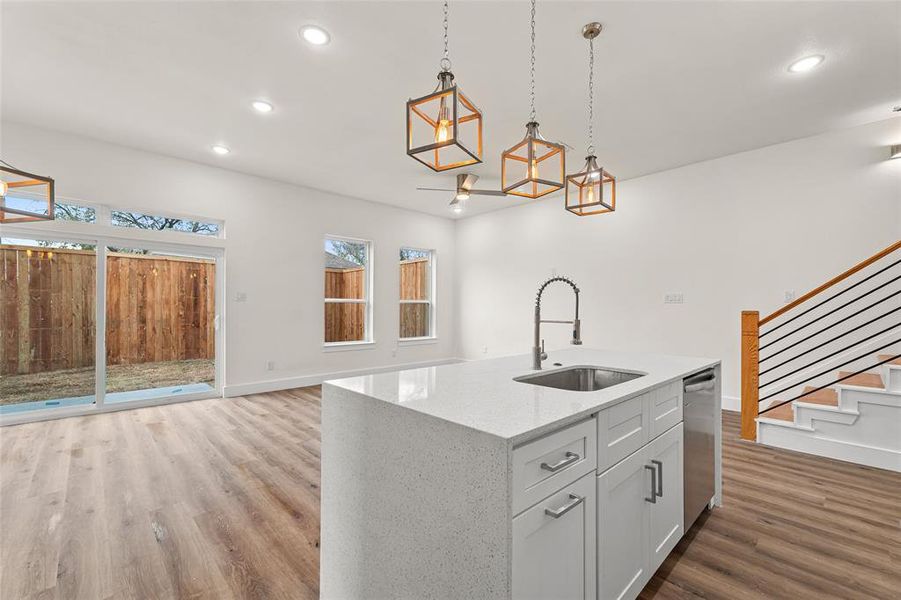 Kitchen featuring light stone countertops, light wood finished floors, white cabinetry, pendant lighting, and recessed lighting Kitchen featuring light stone countertops, light wood finished floors, white cabinetry, pendant lighting, and recessed lighting