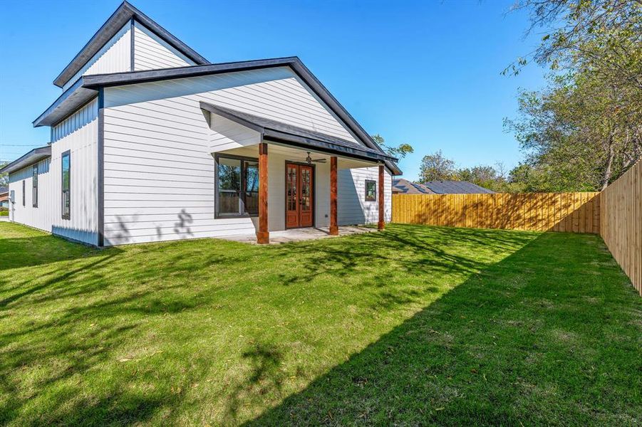 Rear view of house featuring french doors, a lawn, and a patio area