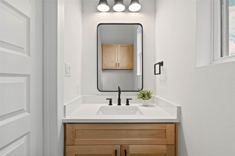 Sleek and streamlined, the powder bath offers natural wood tones and matte black fixtures for a refined yet welcoming look.