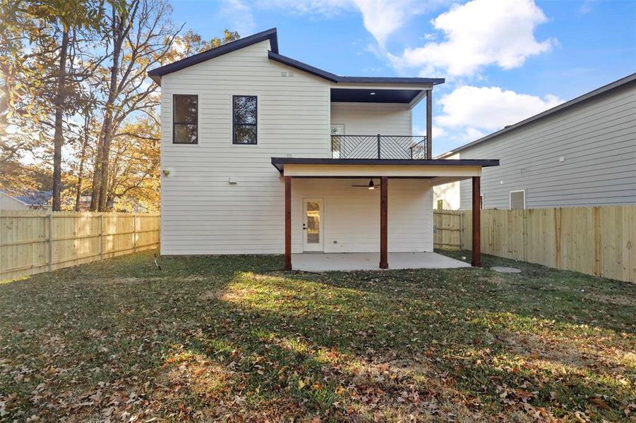 Back of house with a yard, a balcony, and a patio