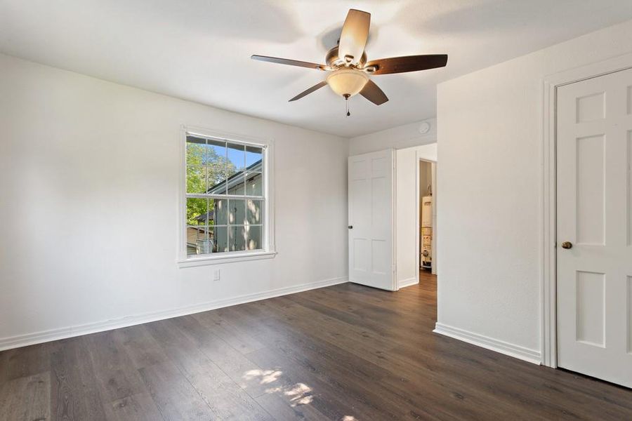 Unfurnished bedroom with dark wood finished floors, baseboards, and ceiling fan