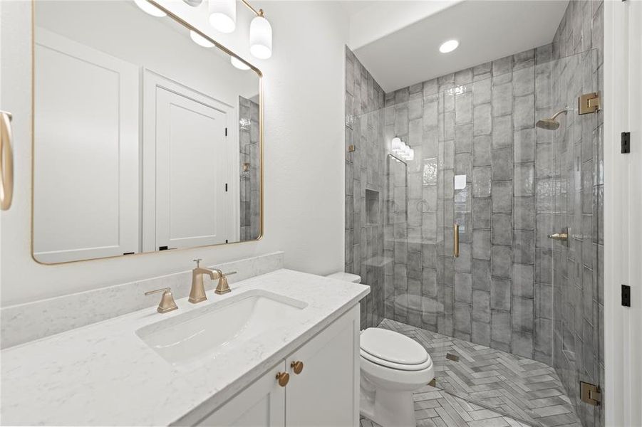Bathroom featuring a white vanity with a quartz countertop, gold-finish hardware, and a framed mirror