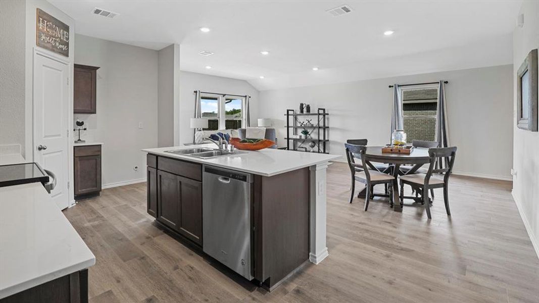 Open-concept living space featuring a central kitchen island with a double sink and stainless steel dishwasher