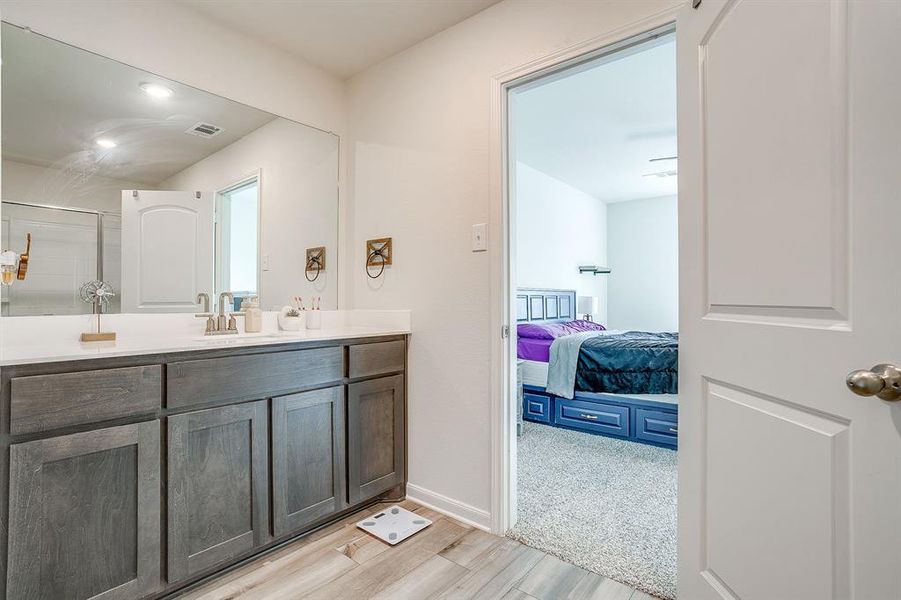 Bathroom featuring vanity, light wood-style flooring, ensuite bathroom, and a shower