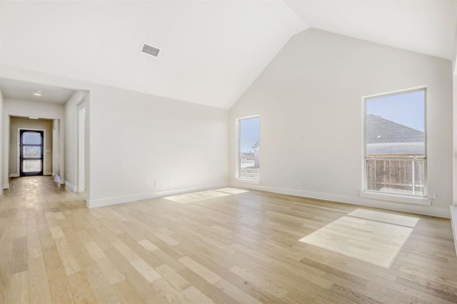 Unfurnished room with a high ceiling, light wood-style flooring, and healthy amount of natural light