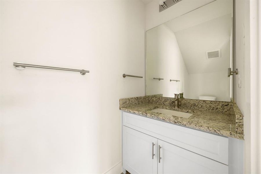 Convenient half bath on the main floor, perfect for guests, featuring a modern vanity, stylish fixtures, and a sleek, space-saving design