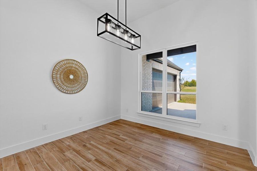 Spare room featuring wood finished floors and a chandelier