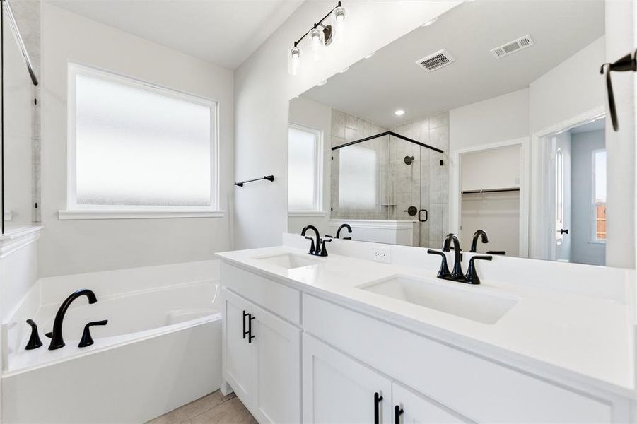 Bathroom with double vanity, a garden tub, a spacious closet, a stall shower, and light tile patterned flooring