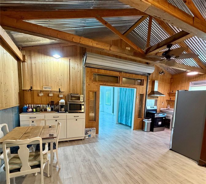 A well-lit kitchen area with natural wood paneling and a corrugated metal ceiling offers a unique, rustic-industrial charm.