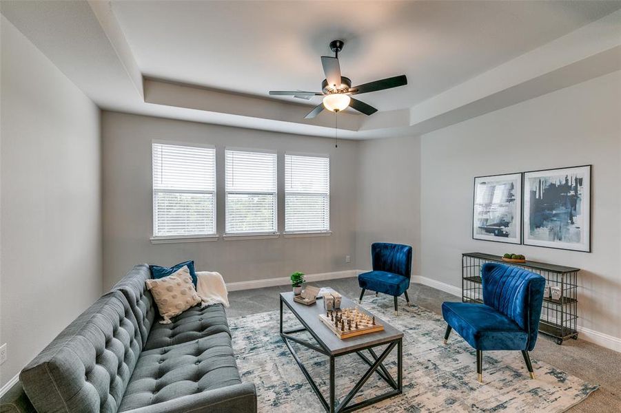 Upstairs living room with carpet, ceiling fan, and a raised ceiling