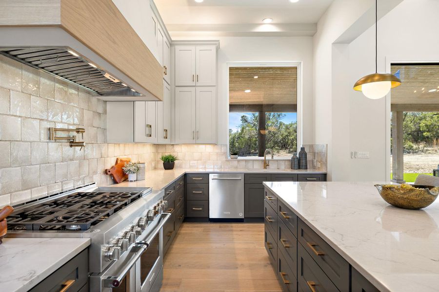 Kitchen featuring appliances with stainless steel finishes, custom range hood, a sink, and tasteful backsplash