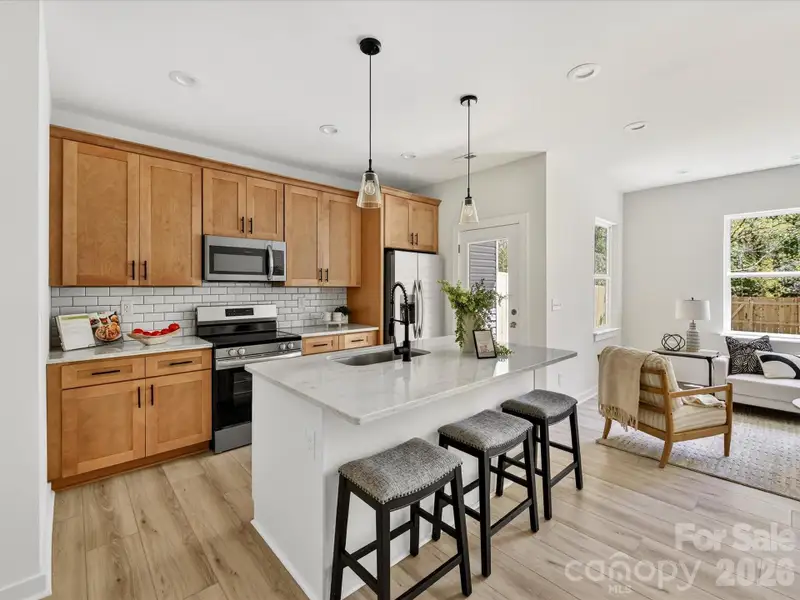 Stylish open-concept kitchen featuring granite countertops, stainless steel appliances, subway tile backsplash, and a spacious island with seating, perfect for everyday living and entertaining. Stylish open-concept kitchen featuring granite countertops, stainless steel appliances, subway tile backsplash, and a spacious island with seating, perfect for everyday living and entertaining.