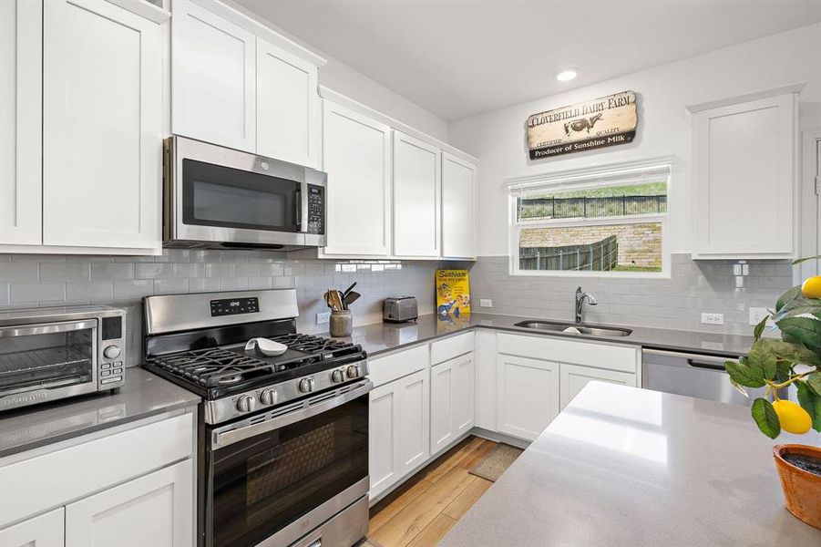 Kitchen with gas cooktop, white cabinetry, and quartz countertops