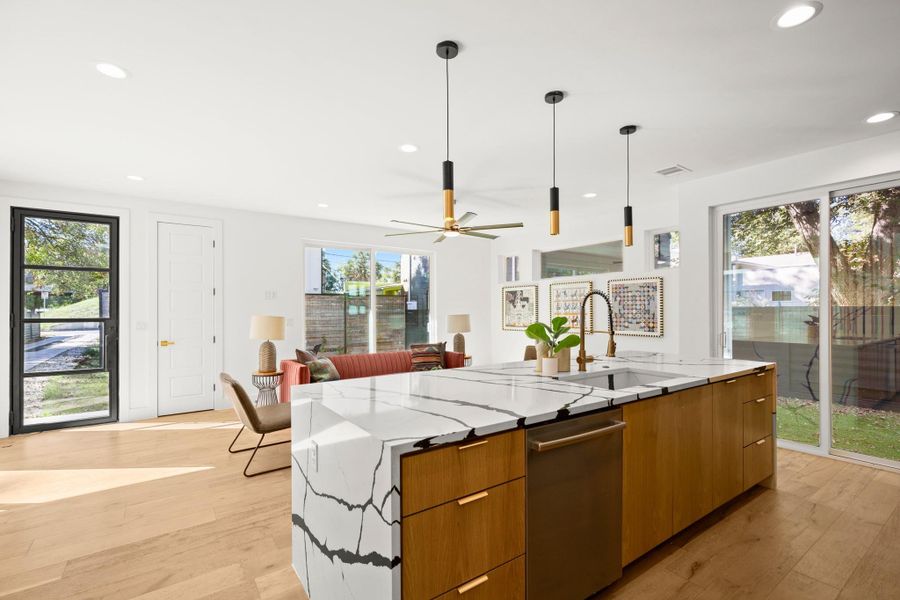 Kitchen featuring modern cabinets, brown cabinets, light wood finished floors, light stone countertops, and recessed lighting Kitchen featuring modern cabinets, brown cabinets, light wood finished floors, light stone countertops, and recessed lighting
