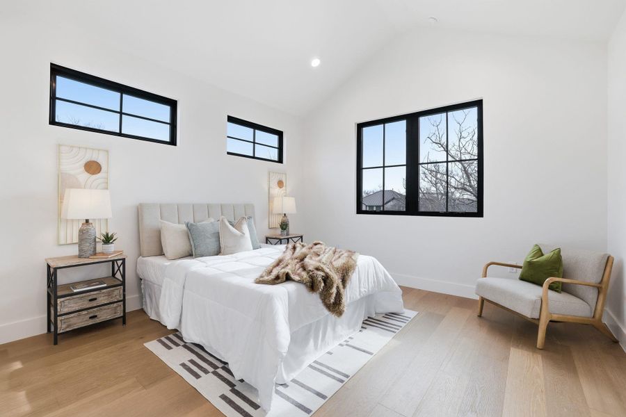Bedroom featuring light wood finished floors, vaulted ceiling, and recessed lighting