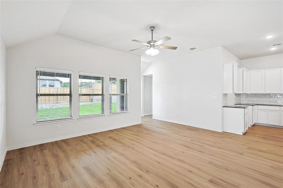 Unfurnished living room with ceiling fan, light wood-type flooring, and lofted ceiling