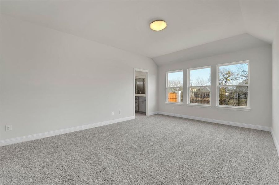 Unfurnished bedroom with lofted ceiling, light carpet, and baseboards