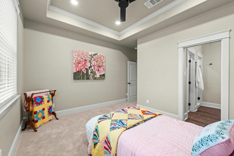 Neutral-toned room featuring a tray ceiling with recessed lighting and a ceiling fan